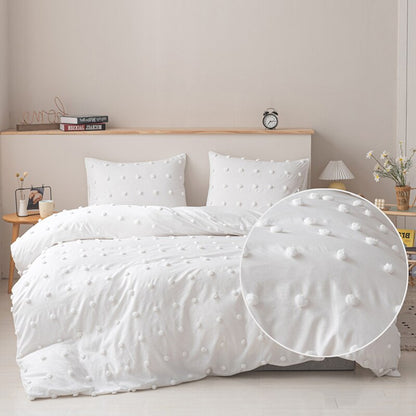 Pom Pom Duvet Cover Set shown in white on a king size bed complete with king sized shams on the pillows.  The picture has a zoomed in shot of the pom pom details.