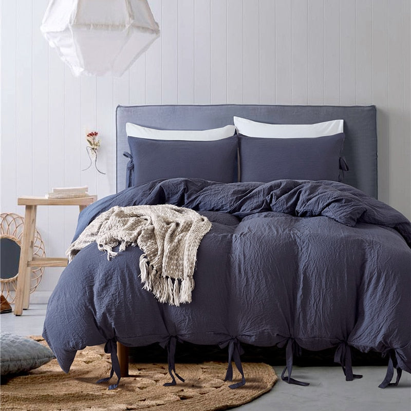Bowtie Lace up Duvet Cover set in dark gray layered with matching pillows and small throw blanket.