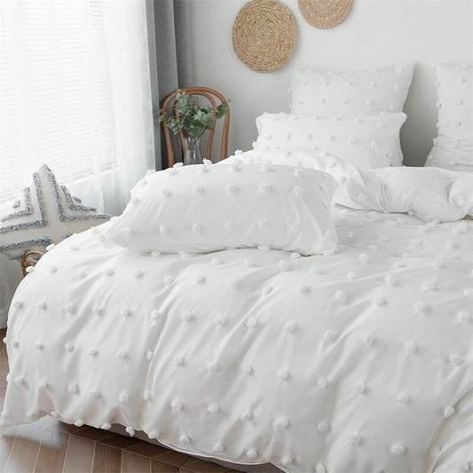 Pom Pom Duvet Cover Set shown in white  on a king size bed complete with king sized shams on the pillows.
