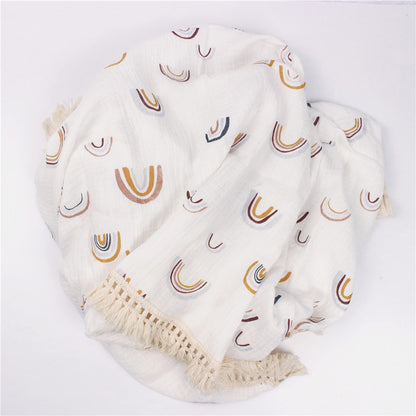 Bamboo and Cotton Muslin Baby Swaddle Blanket.  White background with randomly scattered woodland look rainbows in taupe, golds, and pale blue.  This blanket comes complete with a creamy beige fringed edging.  Available in 2 sizes  47"X40" and 31"X25".